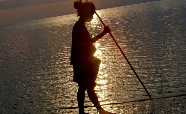 Woman Collecting Fish at Sunset